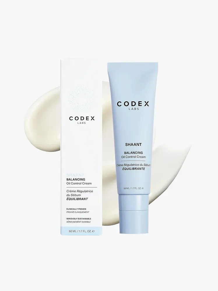 Shaant Balancing Oil Control Cream v modri tubi z blagovno znamko poleg embalaže škatle z blagovno znamko na vrhu vzorca izdelka na svetlo sivem ozadju