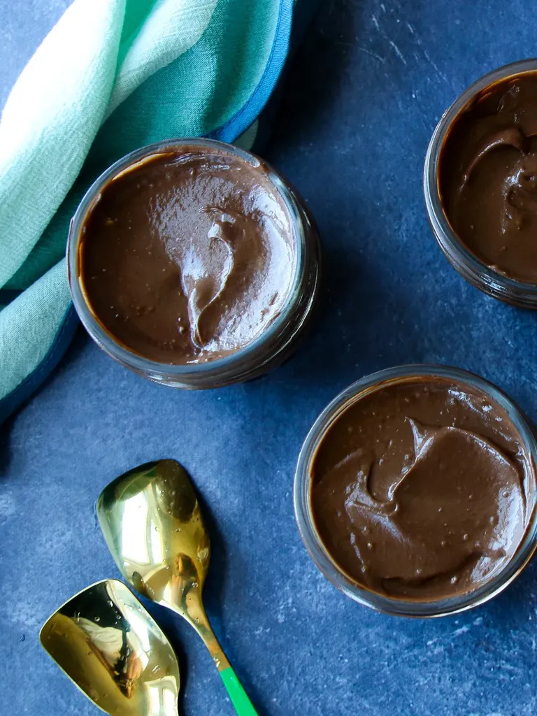 숟가락과 신선한 잘라낸 아보카도가 있는 테이블 위에 초콜릿 아보카도 무스