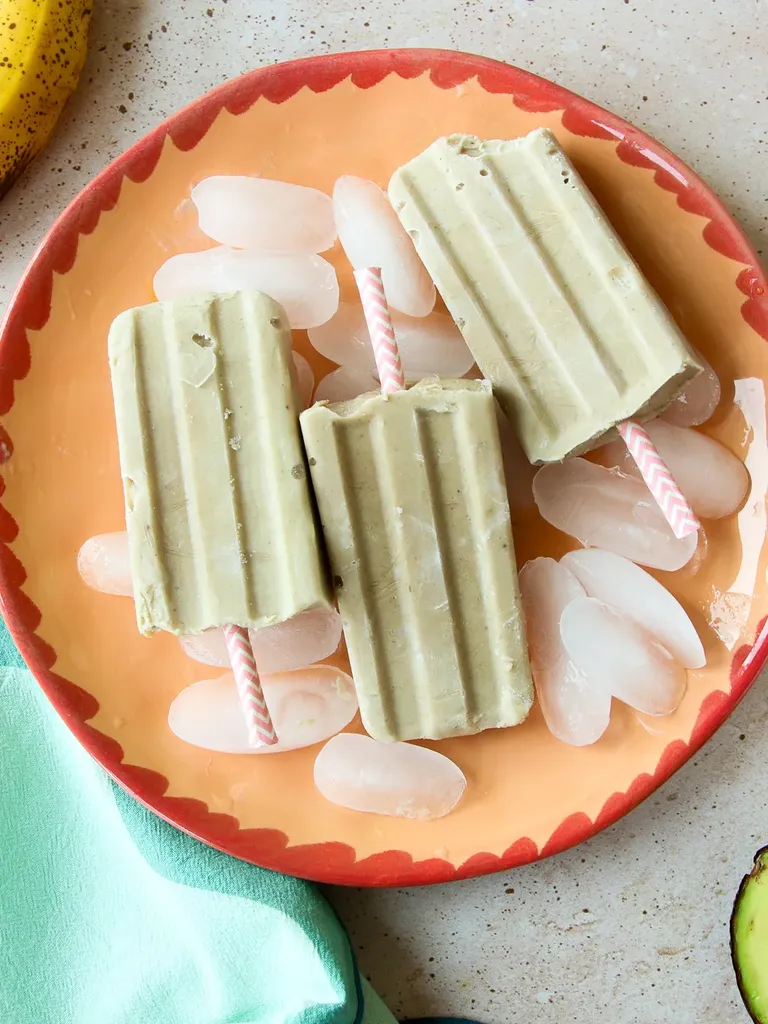 얼음 배경이 있는 접시에 바나나 아이스캔디에는 바나나 아보카도와 냅킨이 있습니다