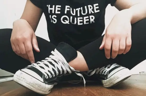 La Rachel asseguda amb les cames creuades amb una camisa negra que diu que el futur és estrany