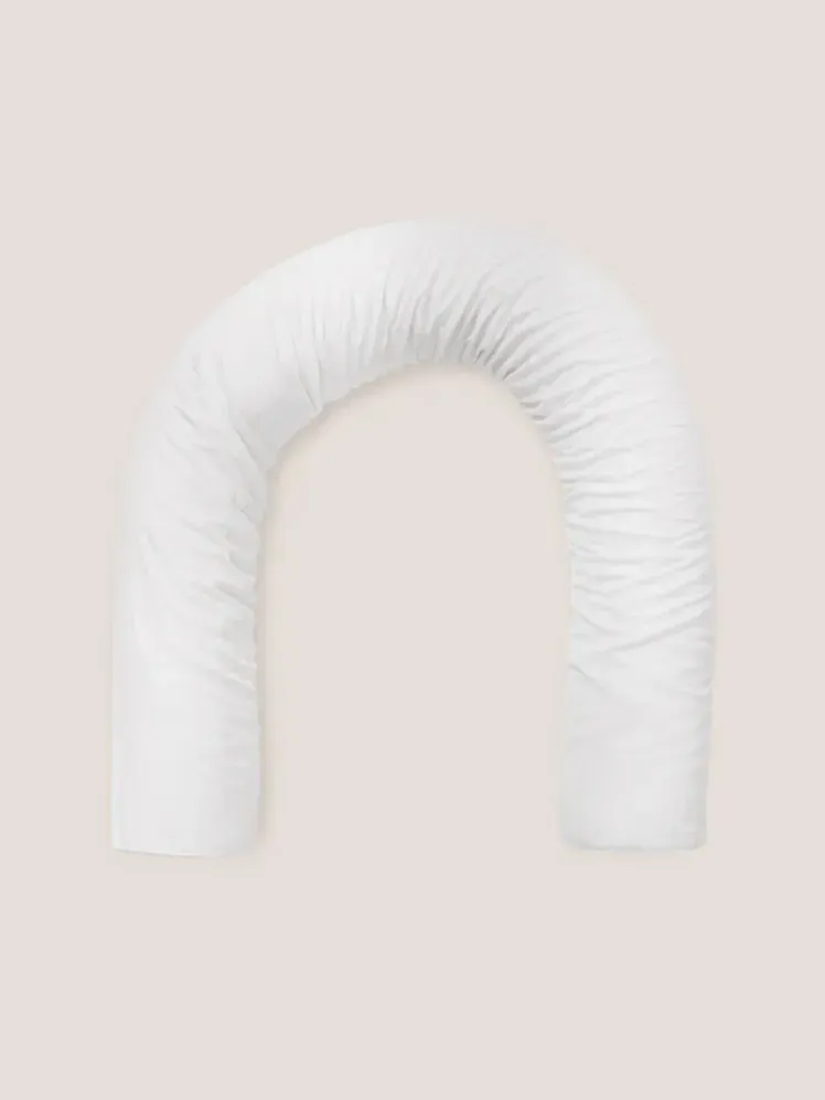 Подушка білого кольору на ніжно-бежевому фоні