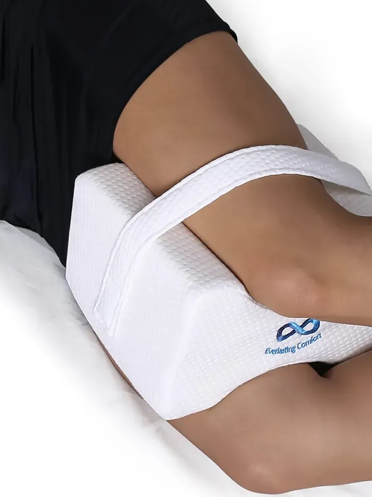 Подушка для колін у фірмовому біло-блакитному кольорі, яку модель використовує на ліжку