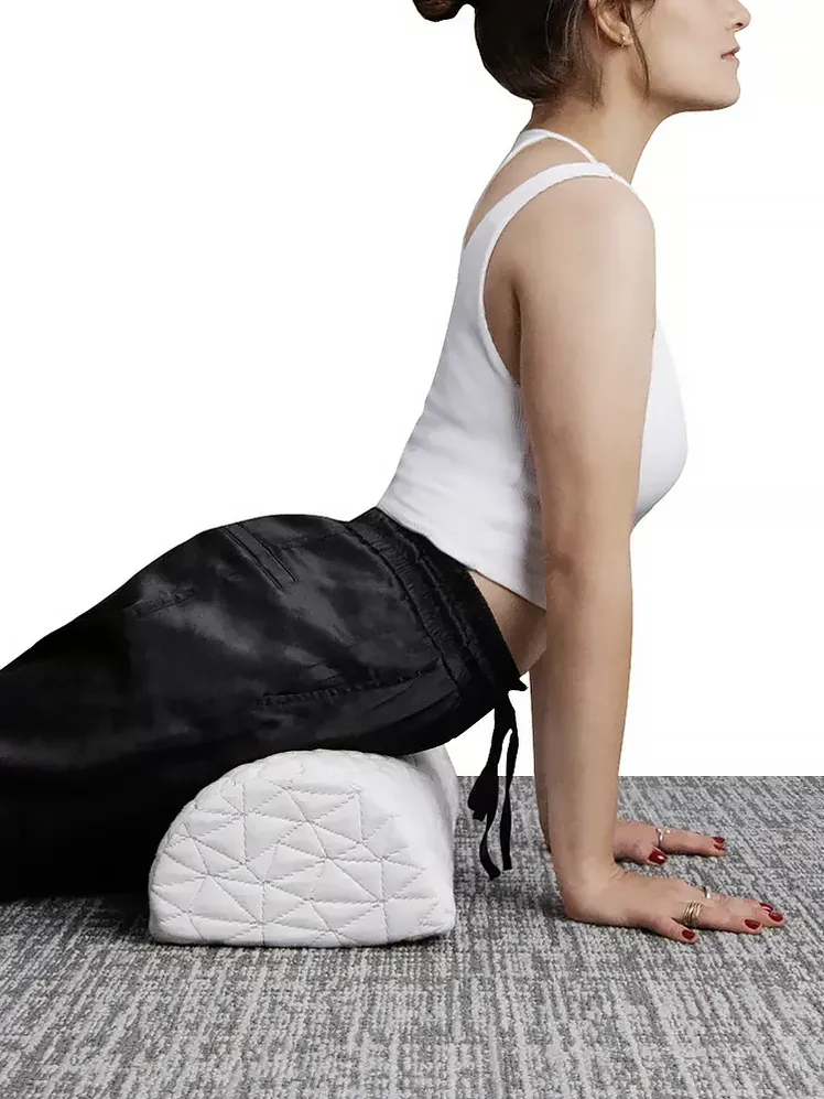 Регульована подушка для колін білого кольору, використана моделлю на текстурованому килимі