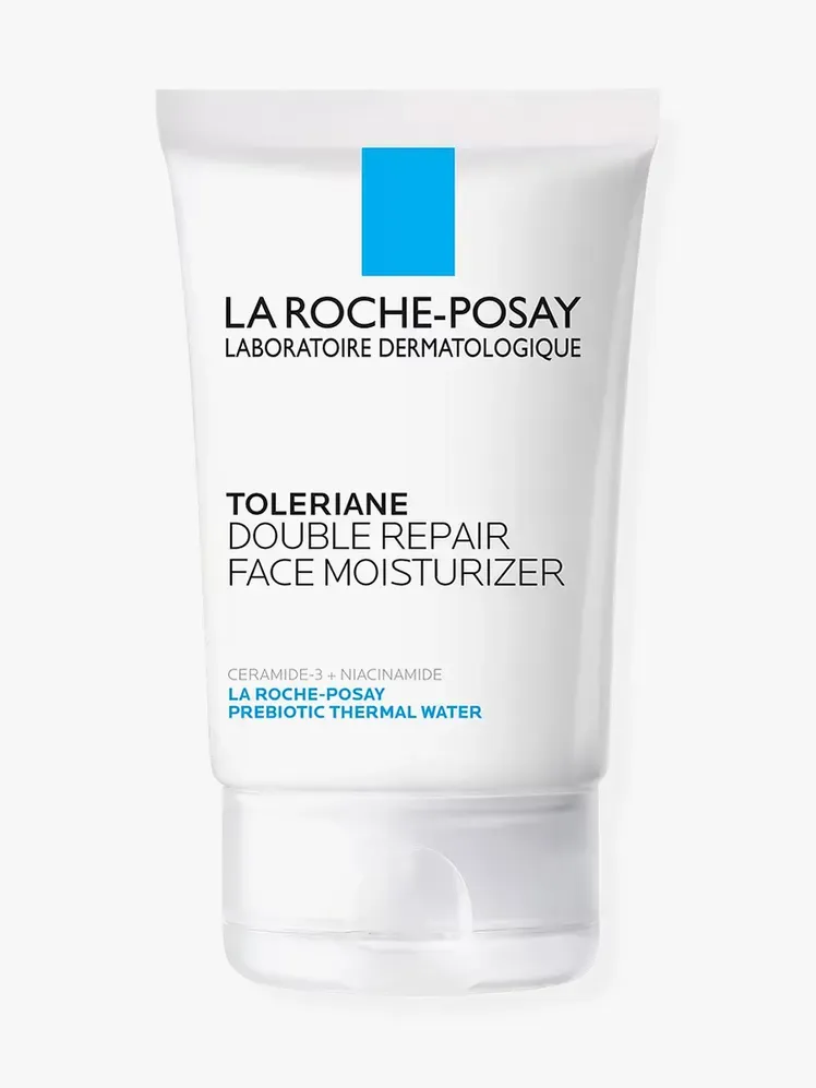 Toleriane Double Repair vlažilna krema za obraz v blagovni znamki bele tube s pokrovčkom na svetlo sivem ozadju