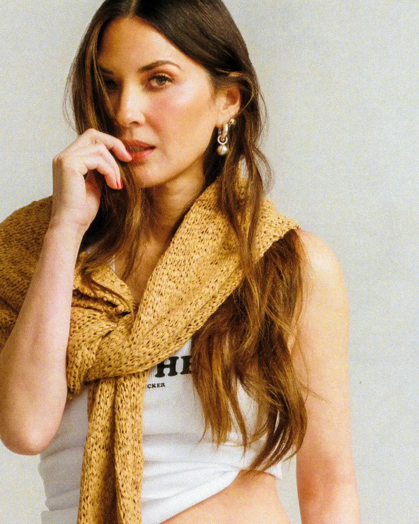 Slika lahko vsebuje fotografijo in portret Olivie Munn, oblačila za odrasle, šal, obraz, glava