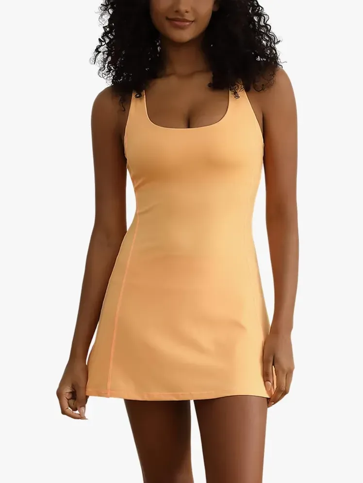 Tenniskjole for trening i myk gul farge på modell på lys grå bakgrunn