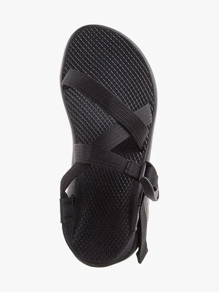 हल्के भूरे रंग की पृष्ठभूमि पर काले रंग में चाको जेड/1 क्लासिक सैंडल