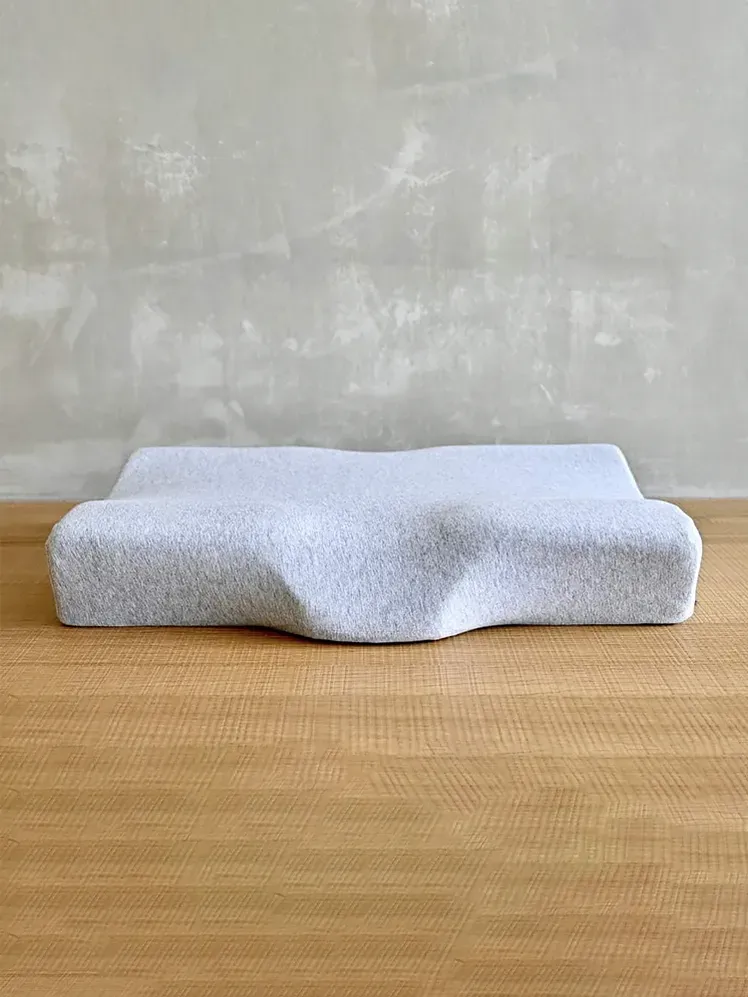 Cushion Lab Neck Relief Ergonomisches Nackenkissen in Grau auf strukturiertem Hintergrund