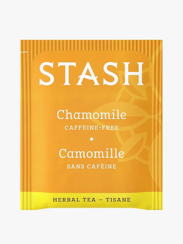 ชาสมุนไพรคาโมมายล์ในซองสีส้มและเหลืองแบรนด์บนพื้นหลังสีเทาอ่อน