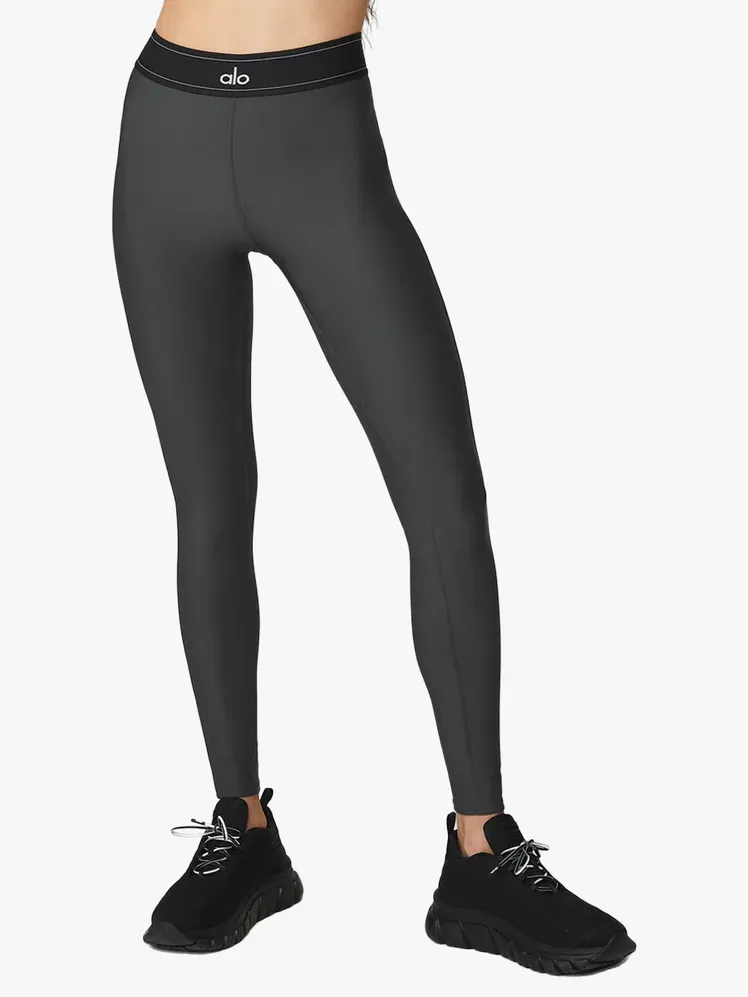 हल्के भूरे रंग की पृष्ठभूमि पर मॉडल पर ग्रे और काले रंग में एयरलिफ्ट हाई-वेस्ट सूट अप लेगिंग