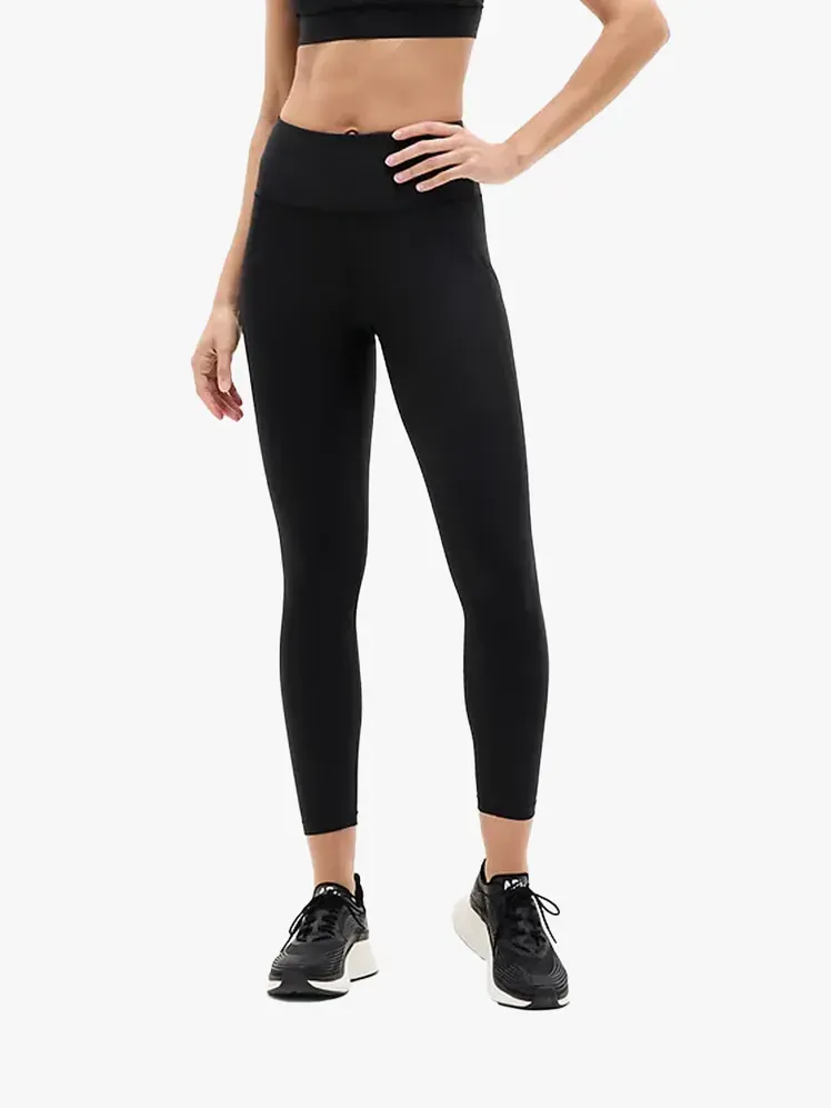 Athleta Interval Stash High Rise Legging 7/8 dalam komponen bermerek dengan latar belakang abu-abu terang