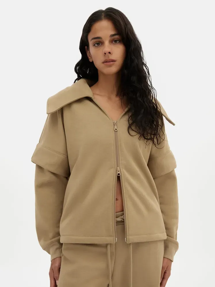 Jaket Berlapis Brulee Macie dengan warna khaki lembut pada model dengan latar belakang abu-abu