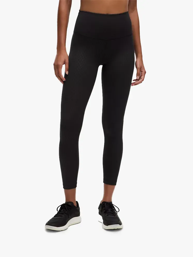 Lululemon Wunder Train High-Rise Tight 25 dalam komponen bermerek dengan latar belakang abu-abu terang