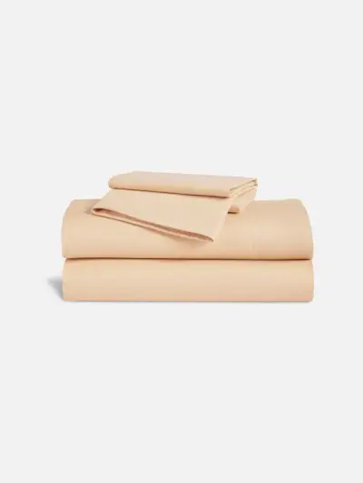 Brooklinen Heathered Cashmere Core Sheet Set in sanftem Blassorange auf grauem Hintergrund