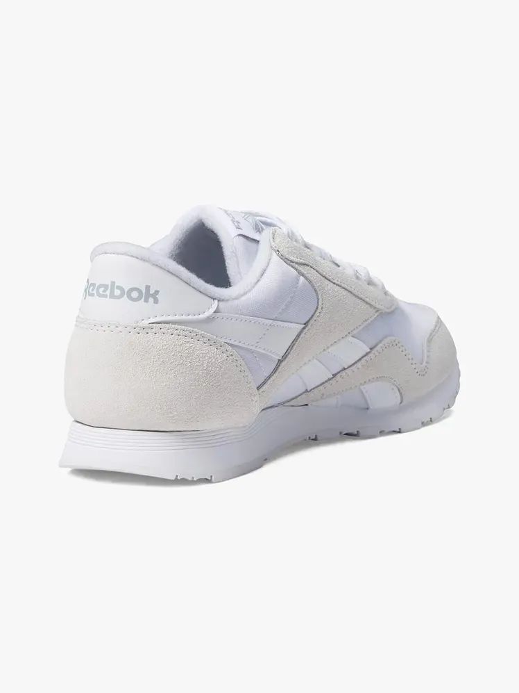 हल्के भूरे रंग की पृष्ठभूमि पर ब्रांडेड घटक में रीबॉक क्लासिक नायलॉन स्नीकर